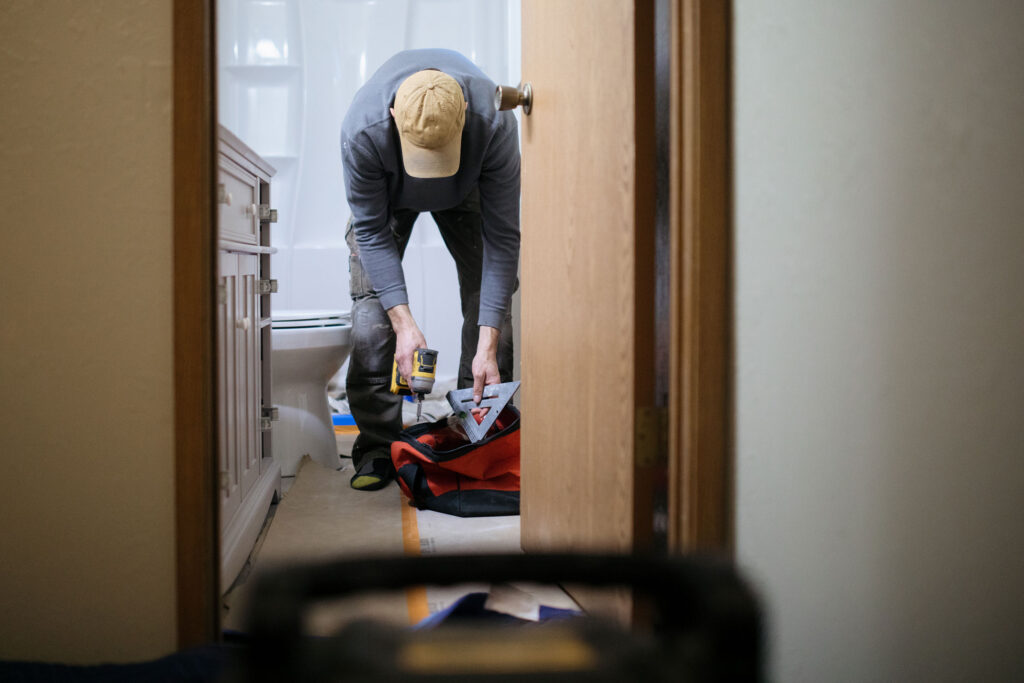 Plumber fixing bathroom vanity in HOA townhome.